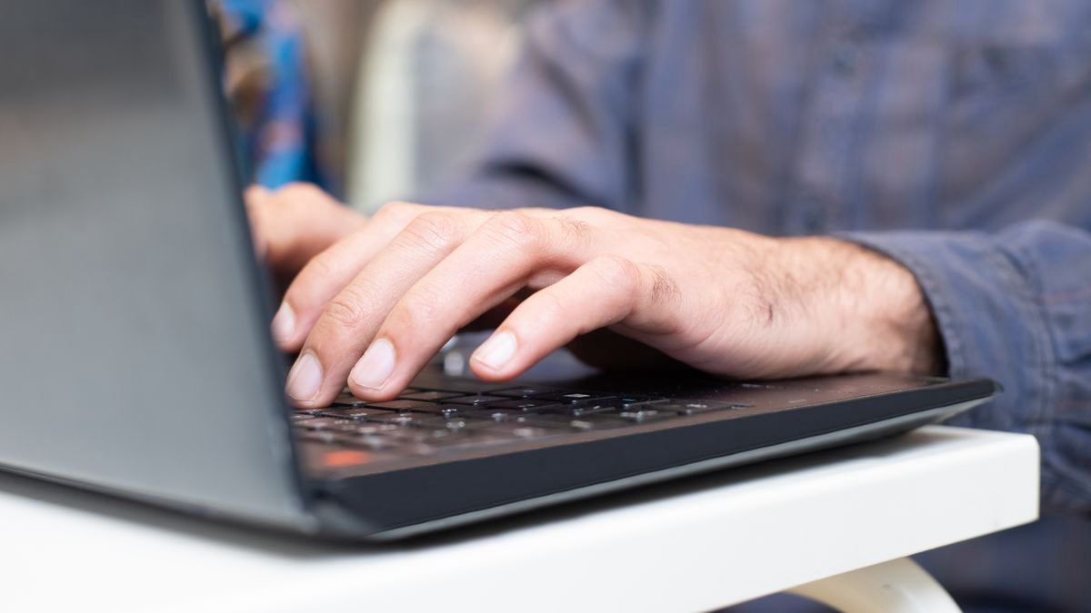 Close-up of hands typing on a laptop keyboard