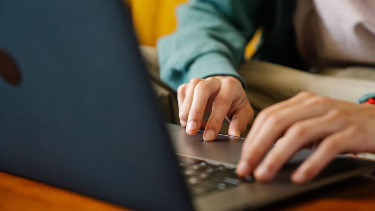 A person working on a small laptop at a desk at home