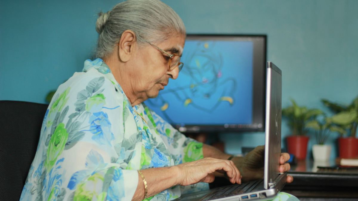 Older woman in a floral saree using a laptop at home