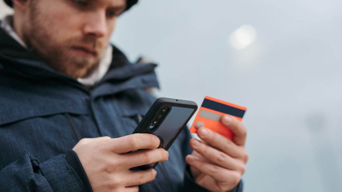 Person entering card details on a mobile phone while shopping online