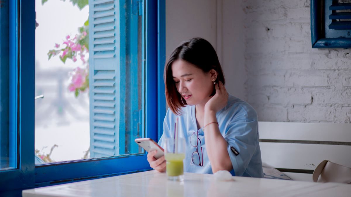 Young woman checking her smartphone by a window in a cafe