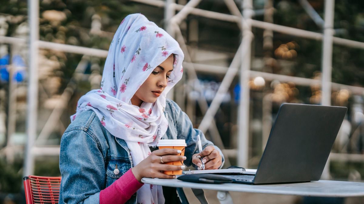 Woman taking notes from her laptop while drinking coffee