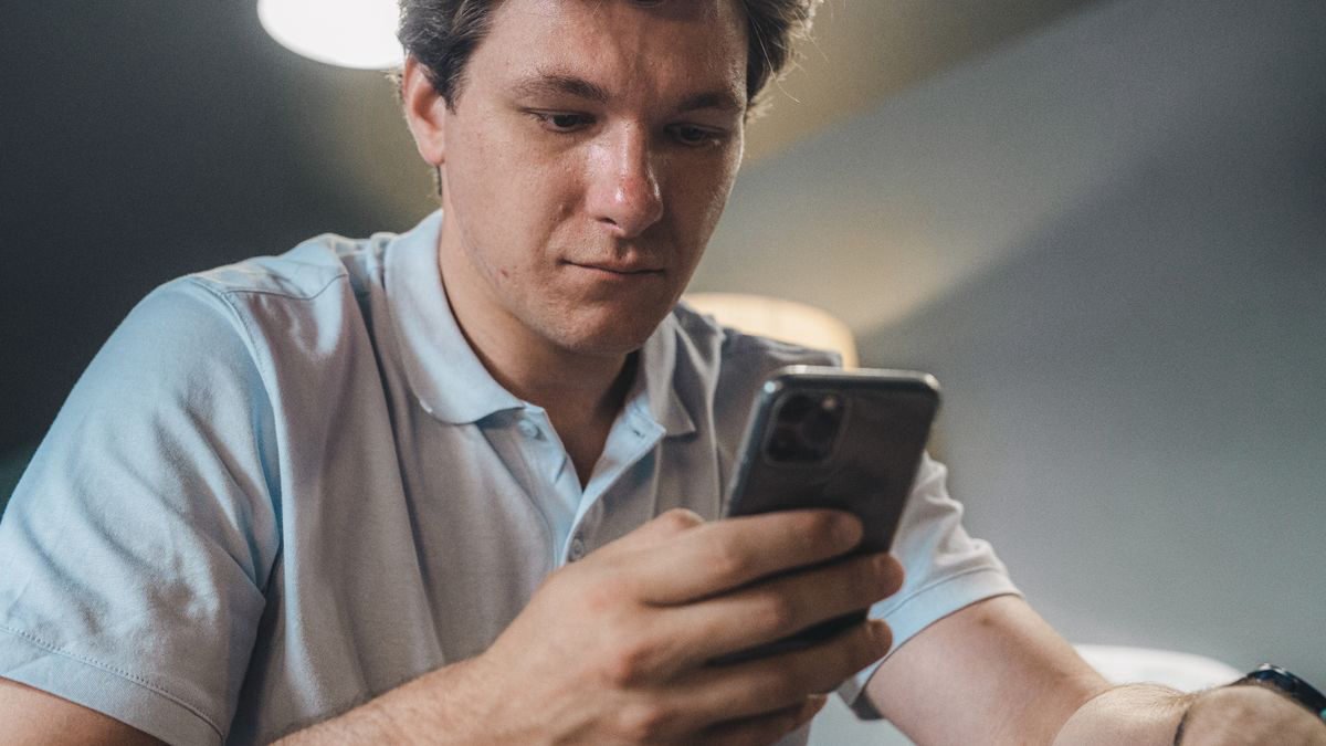 Man in casual clothes using his smartphone indoors
