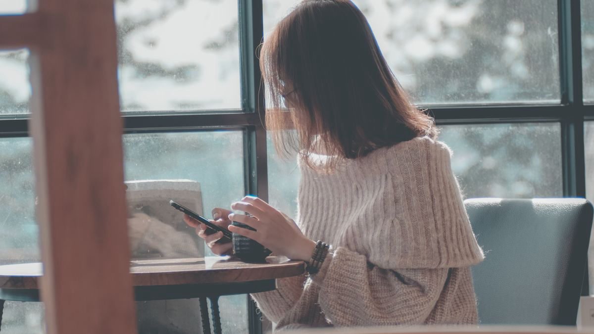 Woman relaxing with a coffee while texting on her smartphone