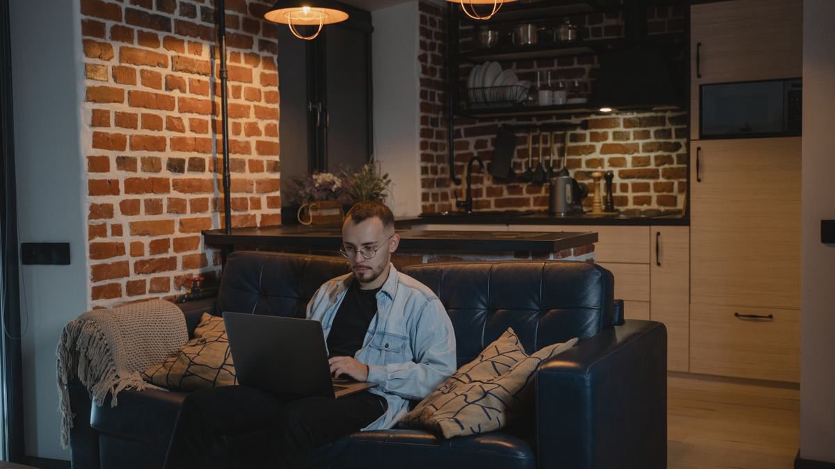 Bearded man sitting on a couch working on his laptop