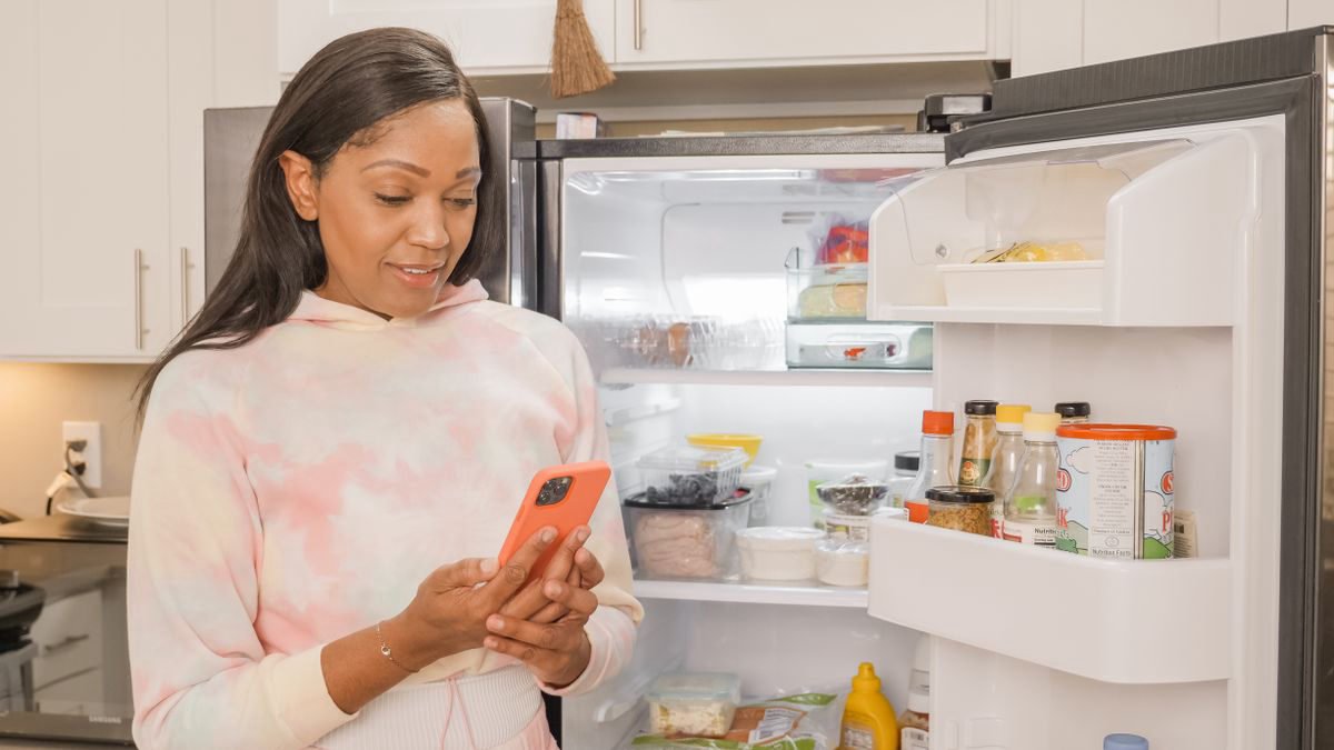Woman using a smartphone while standing in her kitchen