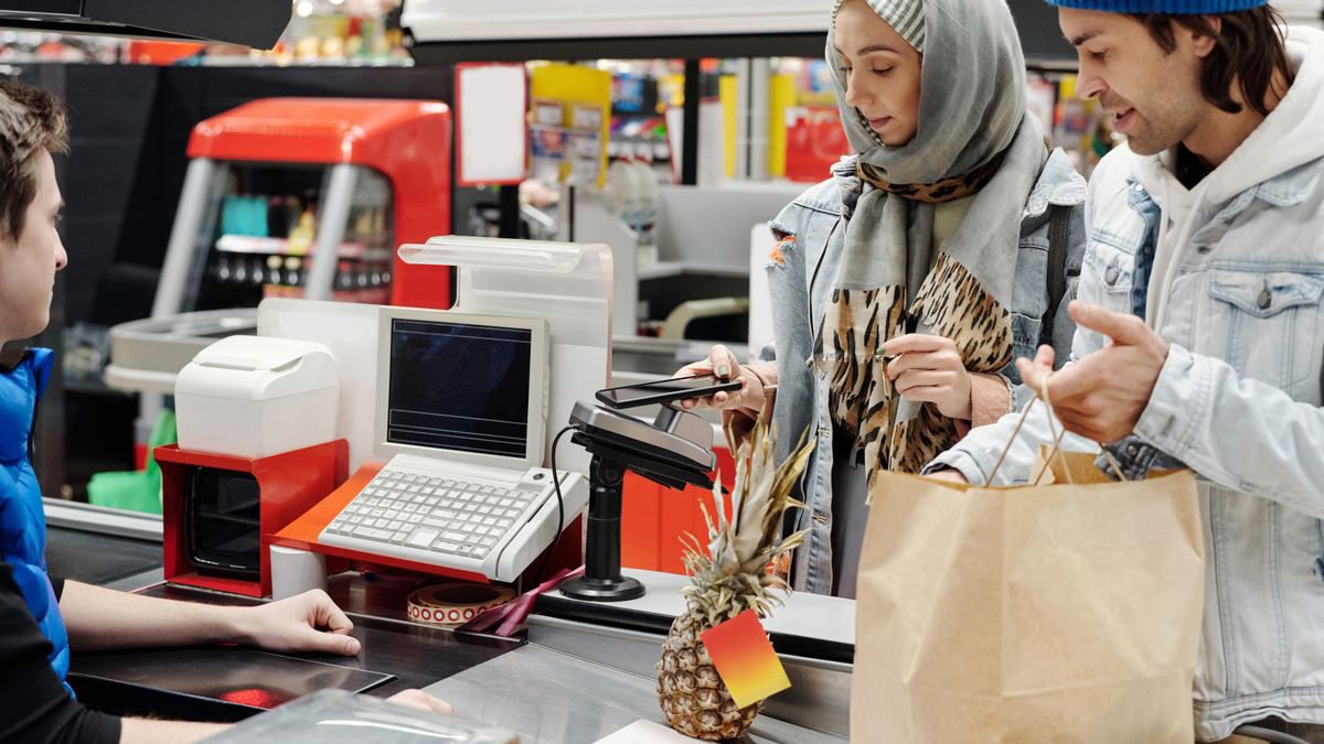 Couple paying with a phone at a supermarket checkout