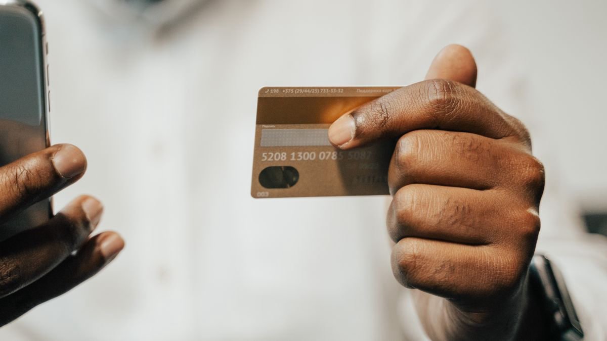 Person using a smartphone and a card to shop online