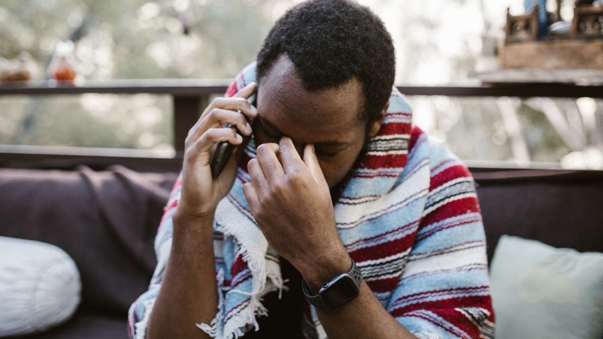 Worried man wrapped in a blanket talking on his phone