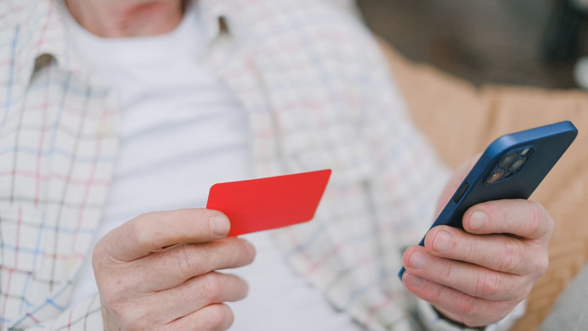 Older adult holding a card and a smartphone at home