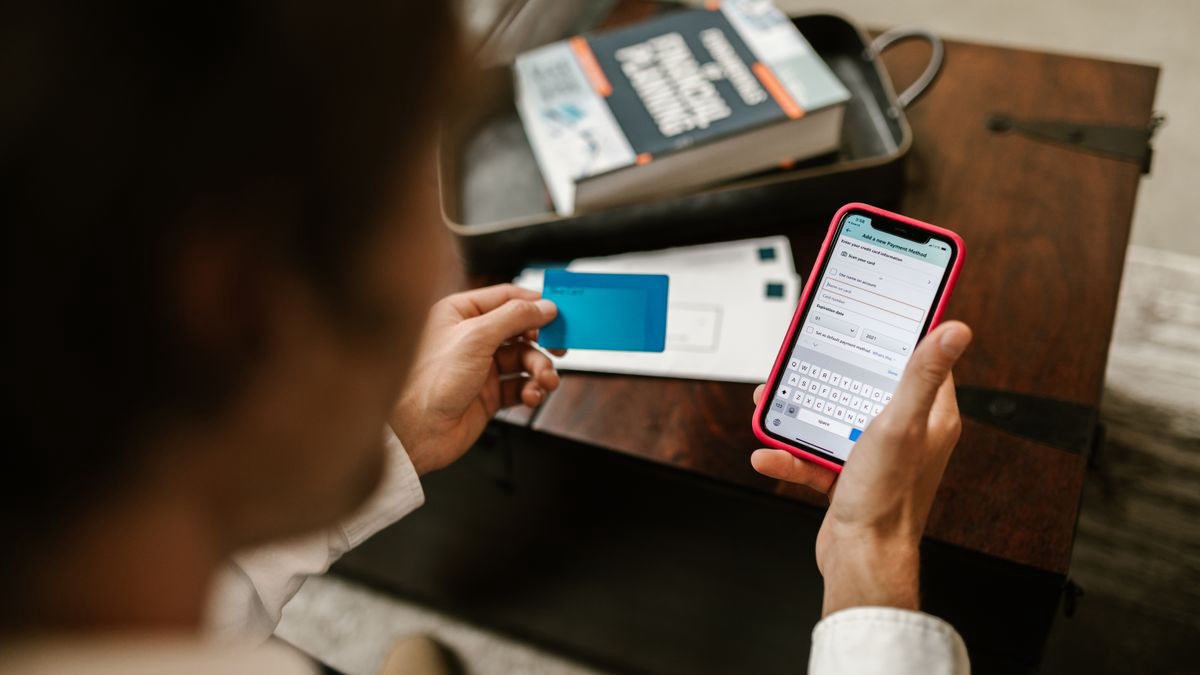 Person paying online with a smartphone and a card