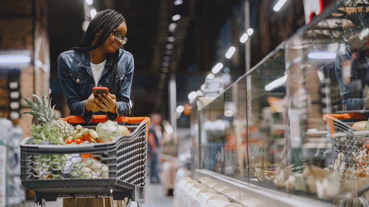 Young woman with braids pushing a shopping cart through a supermarket