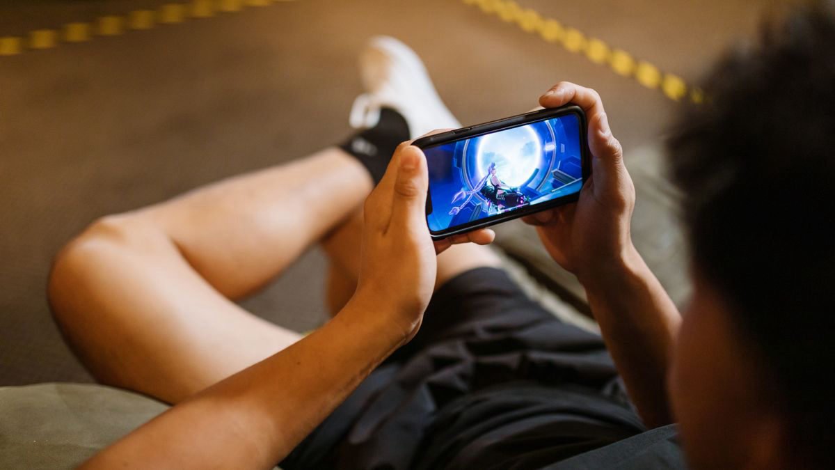 Man sitting comfortably and playing a game on his smartphone