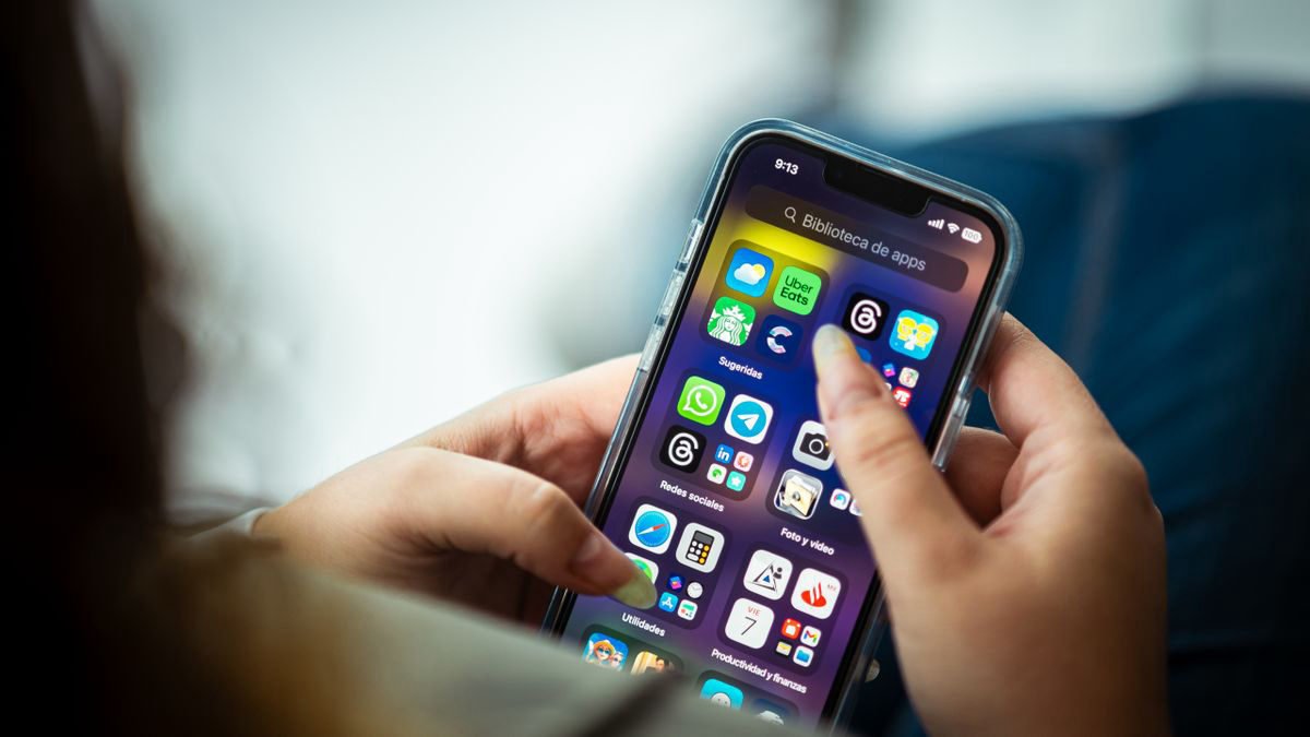 Close-up of a woman holding a smartphone with apps on the screen