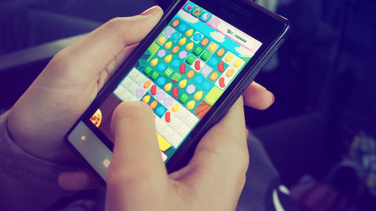 Hands holding a smartphone showing a colourful puzzle game