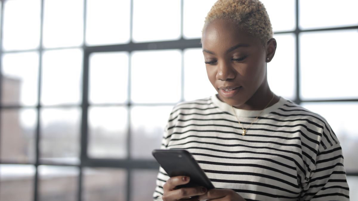 Young woman reading a message on her smartphone by a window