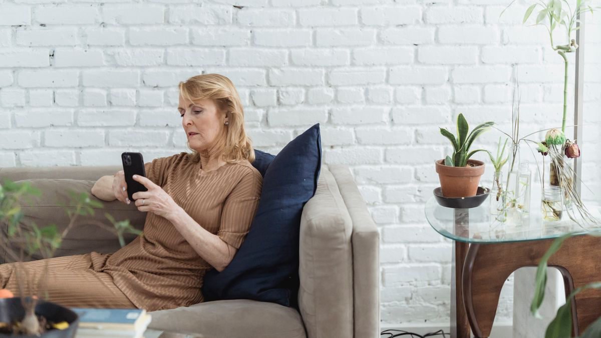 Older woman browsing on her phone while sitting on a couch