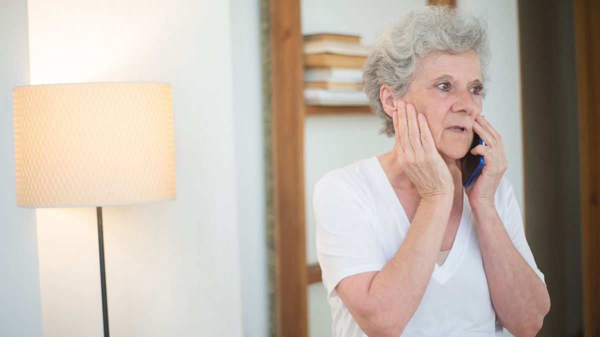 Elderly woman with white hair talking on the phone, looking concerned