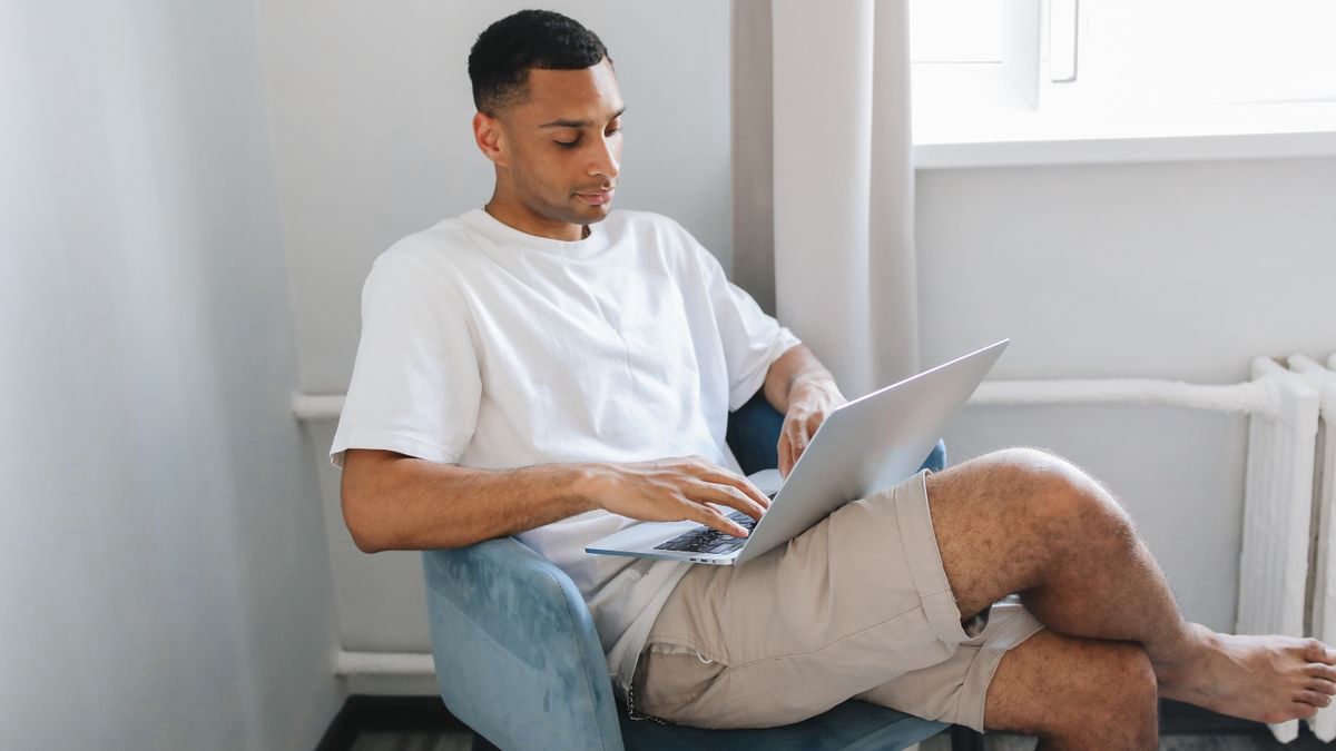 A young man typing on a laptop at home