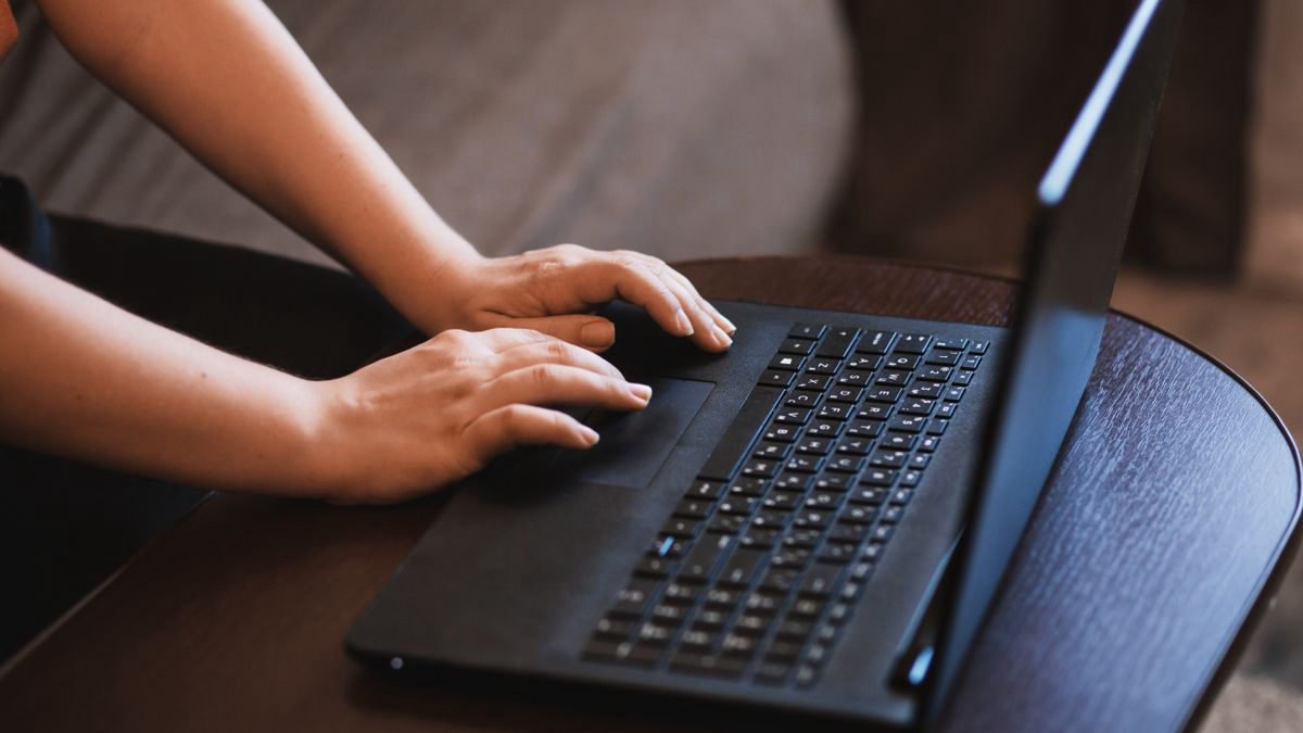 Close-up of hands typing on a laptop