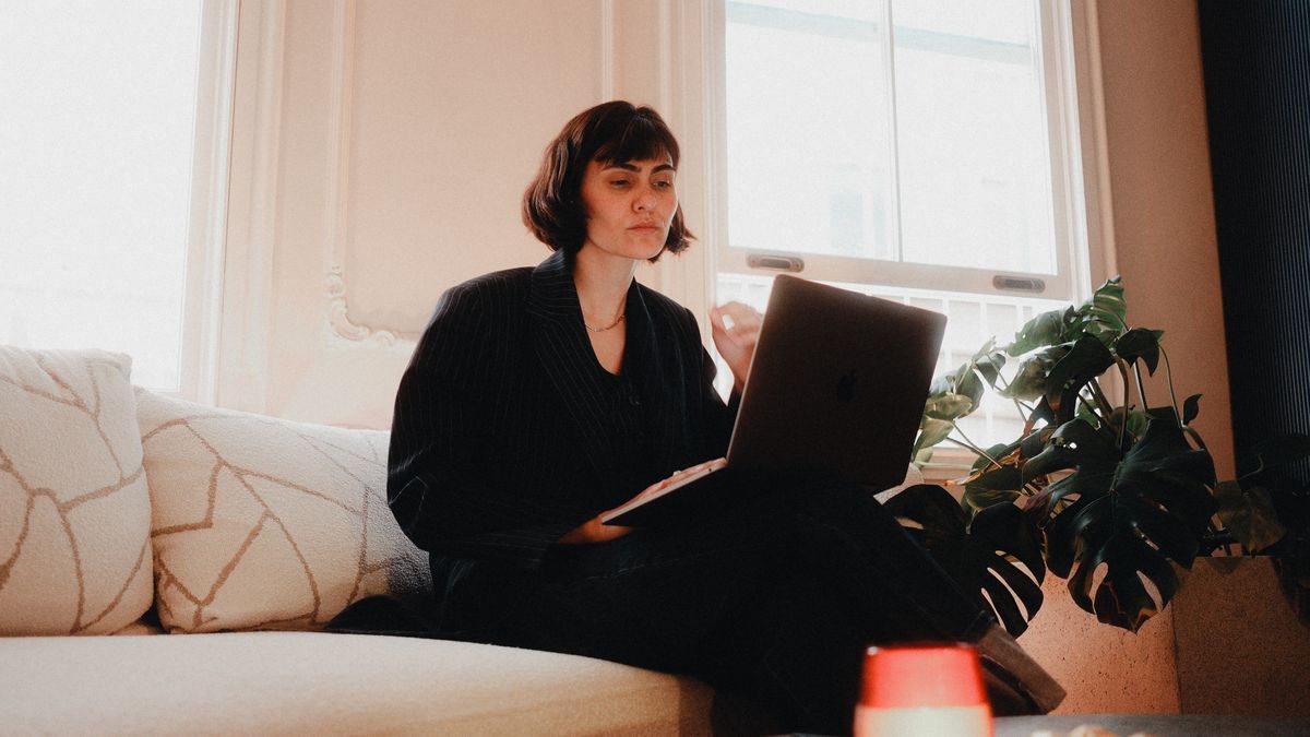 Woman using a laptop on a sofa in a bright room