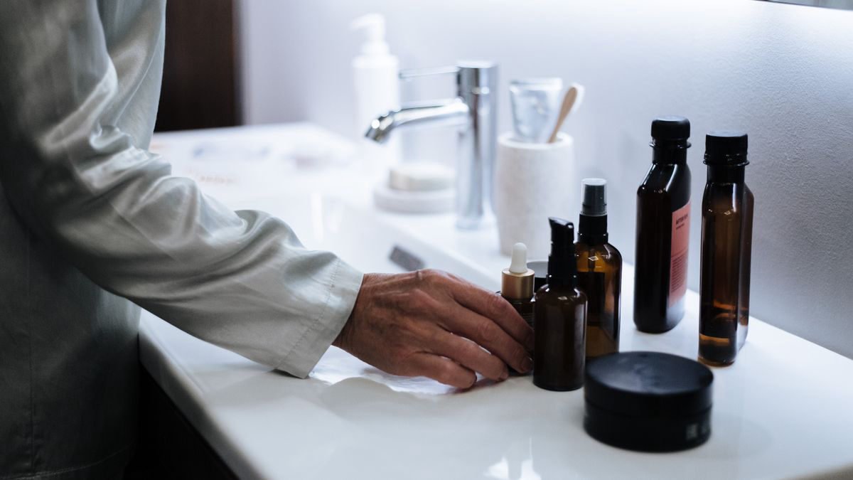 Hand reaching for skincare products on a bathroom counter