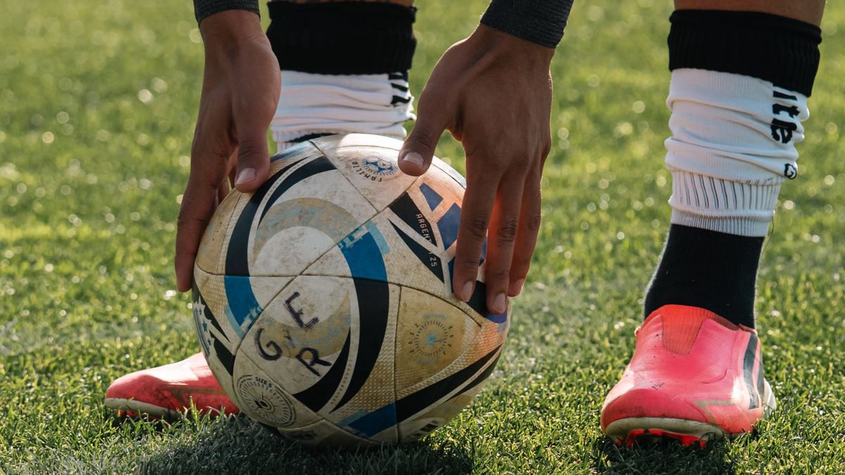 Close-up of a soccer player setting the ball on the grass before a shot