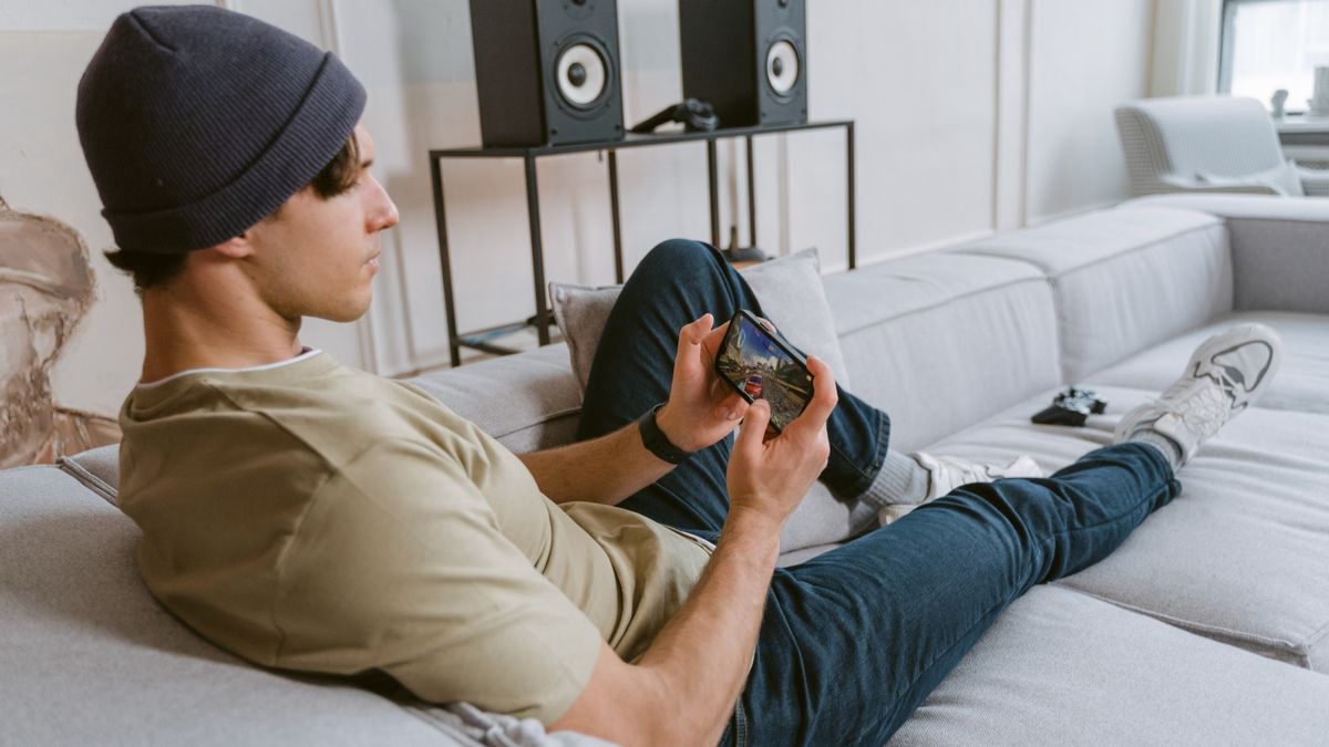 Man relaxing on a sofa playing a game on his phone