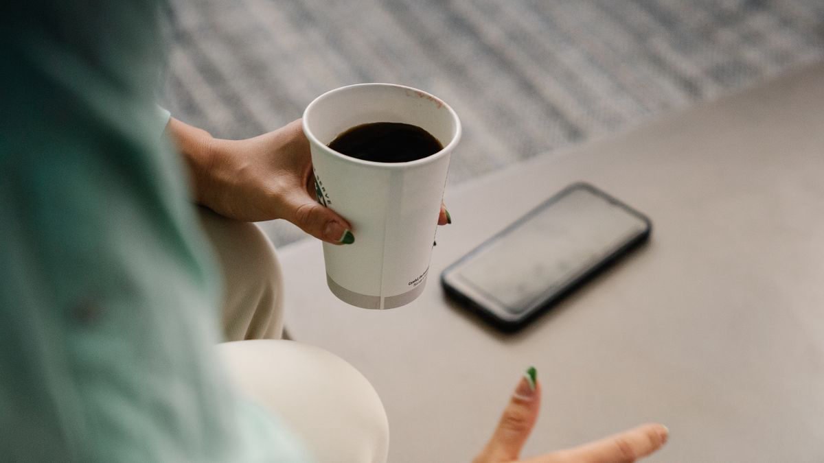 Woman with a coffee cup and smartphone on a morning break