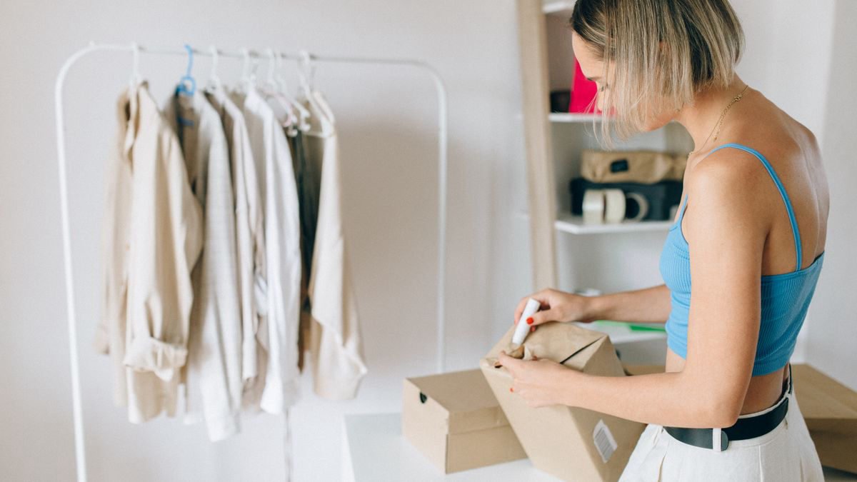 Woman packing clothes into a box in a bright room