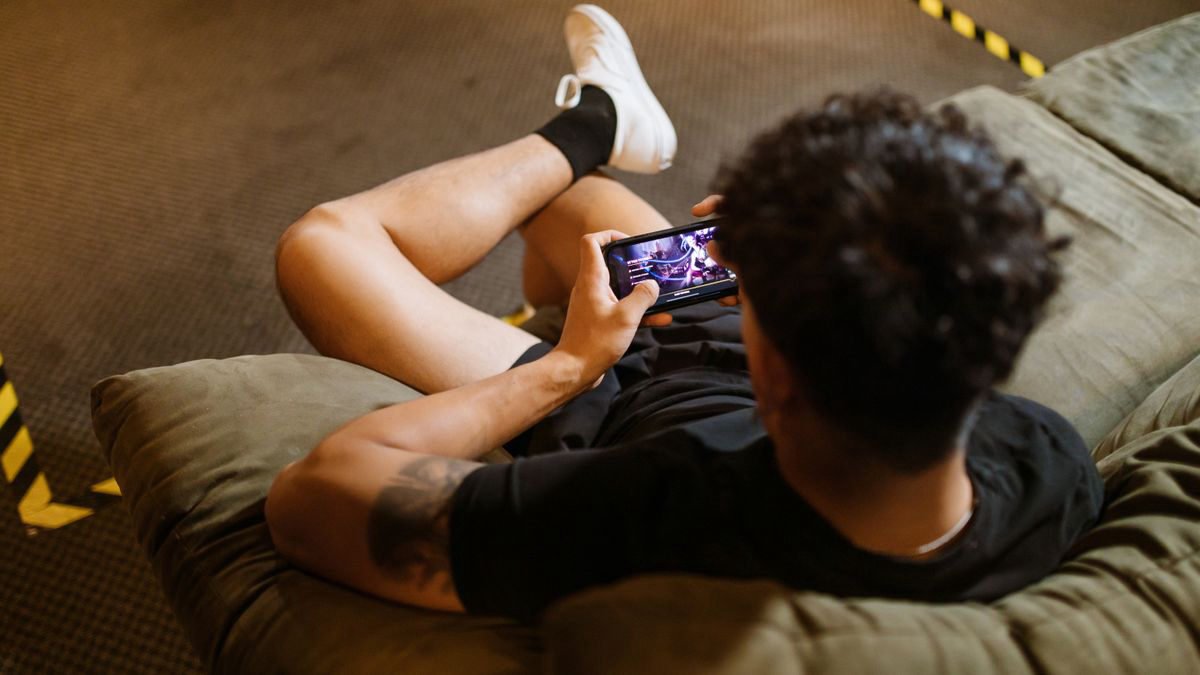 Man relaxing on a sofa and playing a game on his smartphone