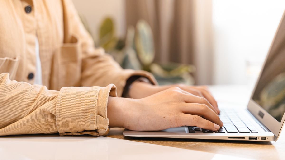 Close-up of hands typing on a laptop indoors