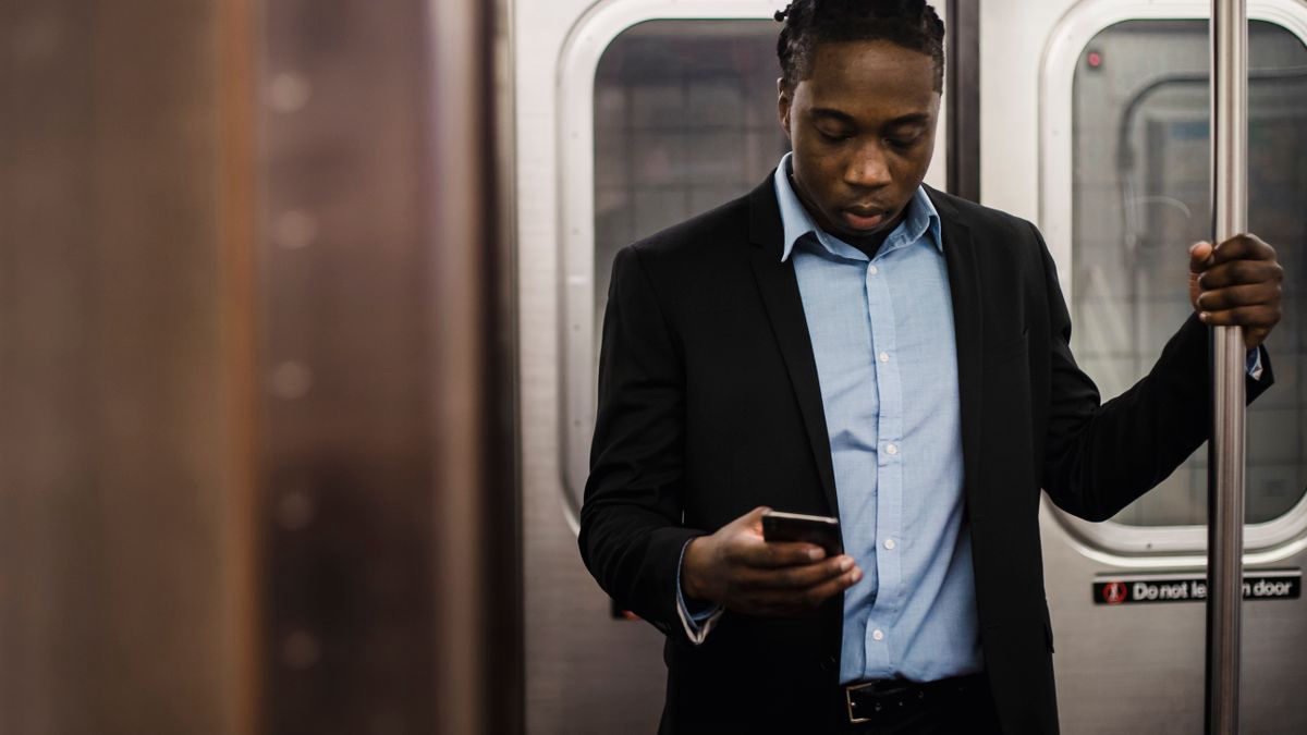 Office worker using his phone while getting home on public transport