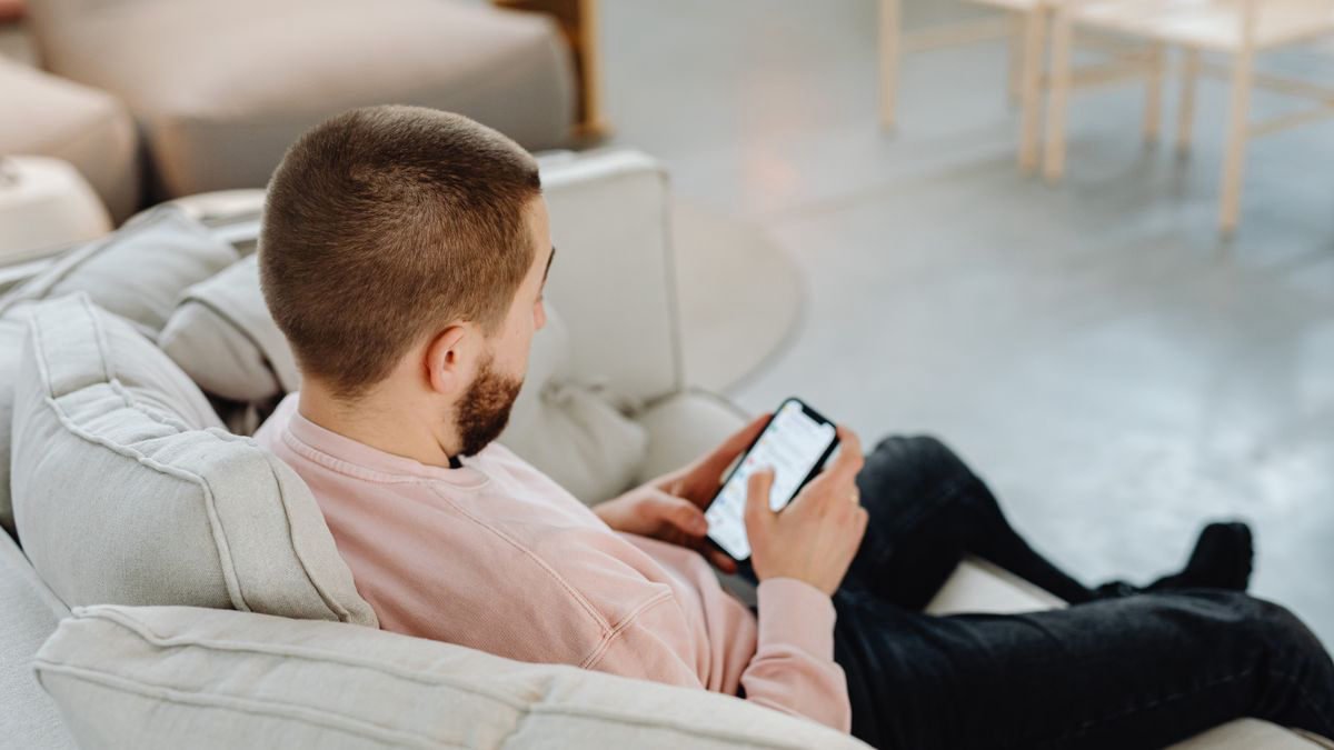 Man sitting comfortably on a couch browsing on his smartphone