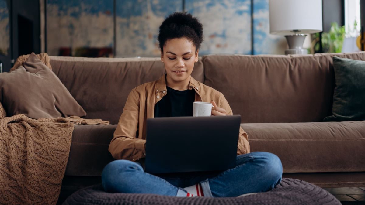 Woman sitting on a sofa with a laptop and a cup
