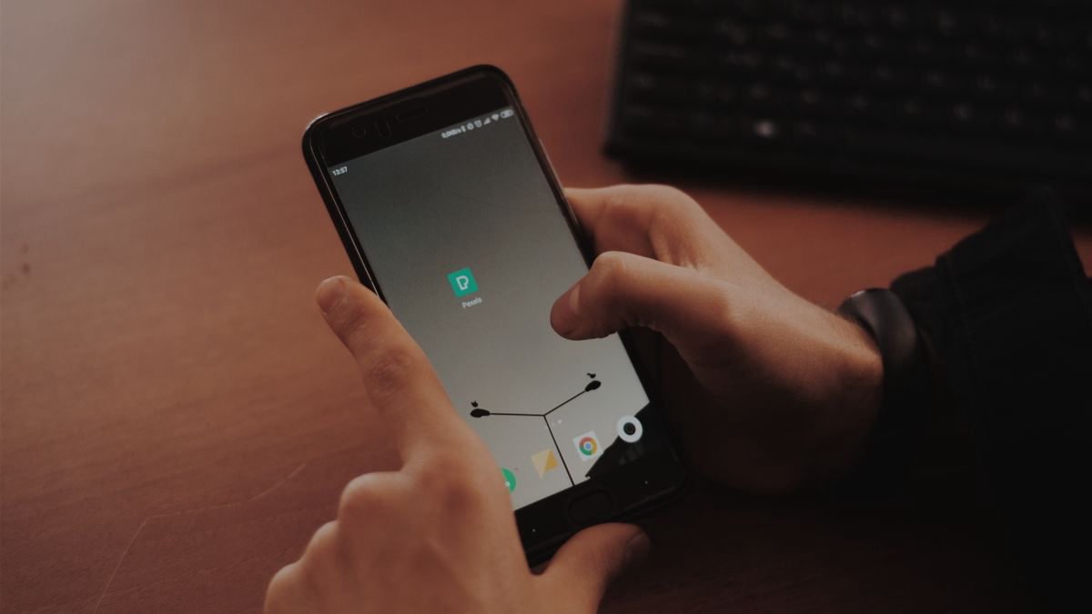 Hands using a smartphone on a wooden desk