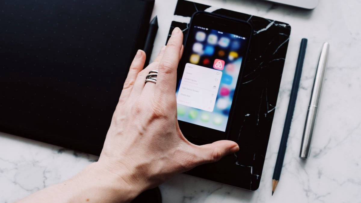 Person browsing a mobile phone while working at a desk, seen from above