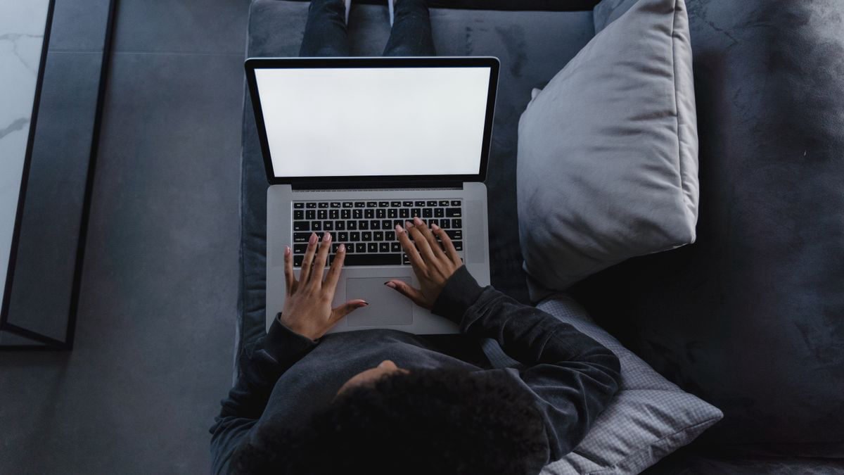 Person using a laptop while sitting comfortably on a couch at home