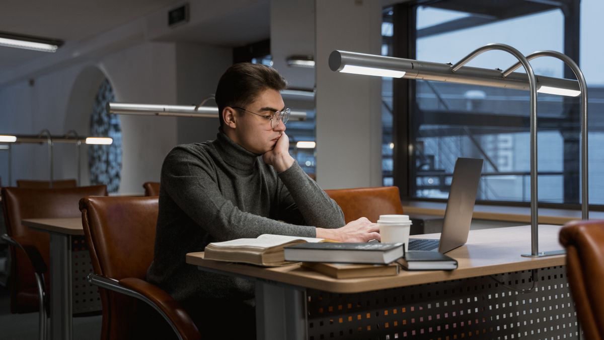 Young man working on a laptop in a quiet university library