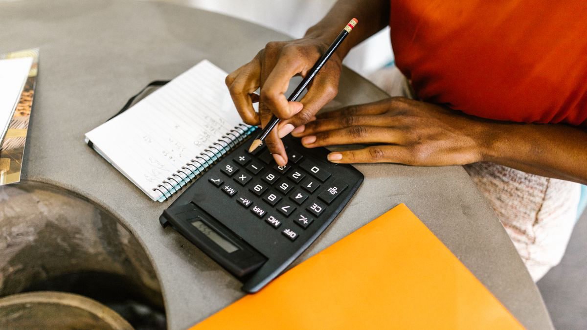 Woman using a calculator and notepad to plan a budget