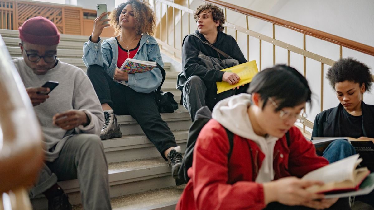 College students sitting on stairs, studying and using their phones