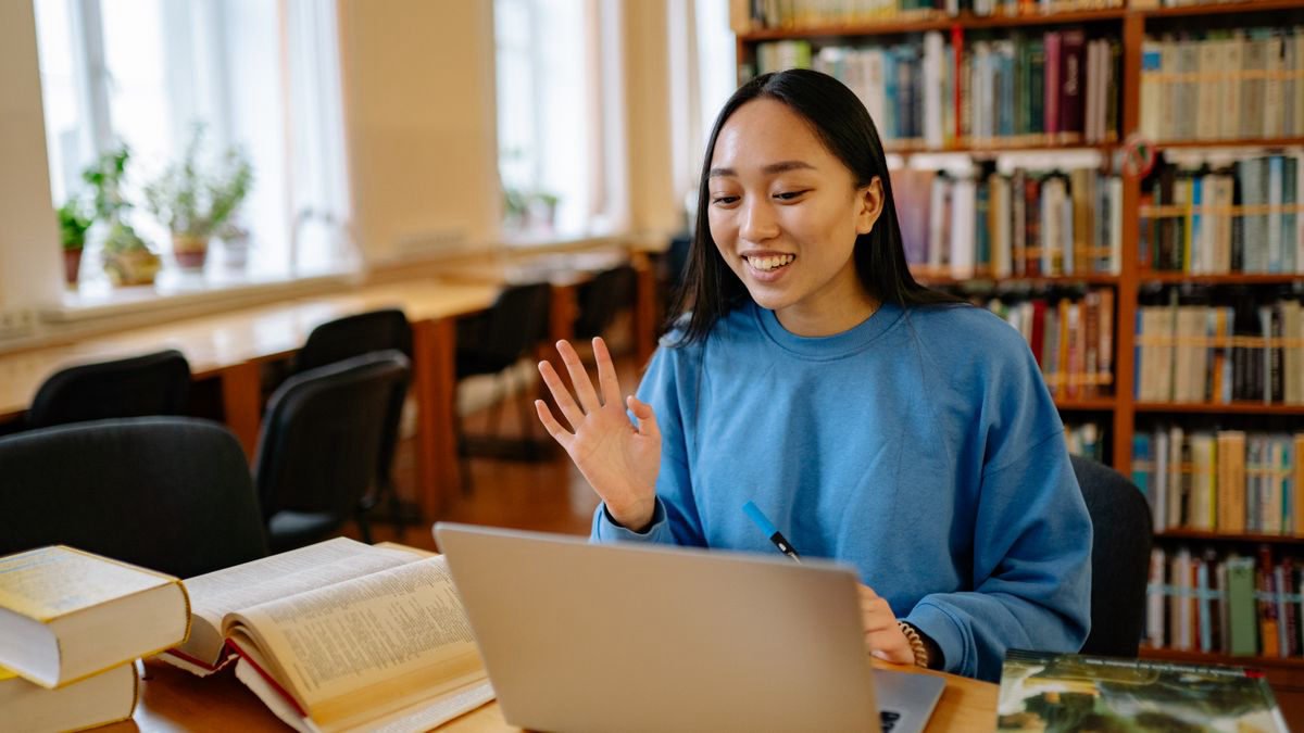 Smiling student using a laptop in a library