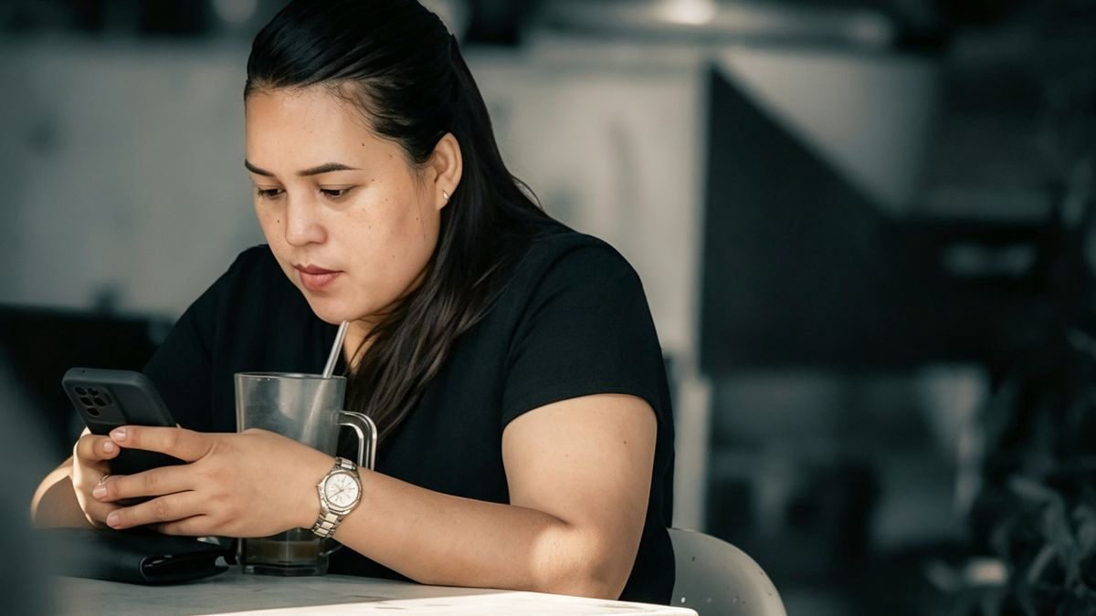 Woman sipping iced coffee while using her smartphone in a cafe
