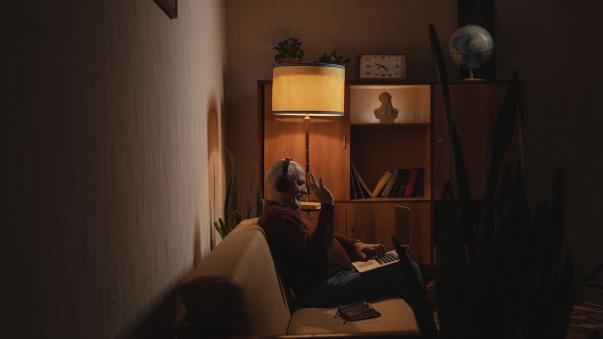 Older man sitting on a couch using a laptop