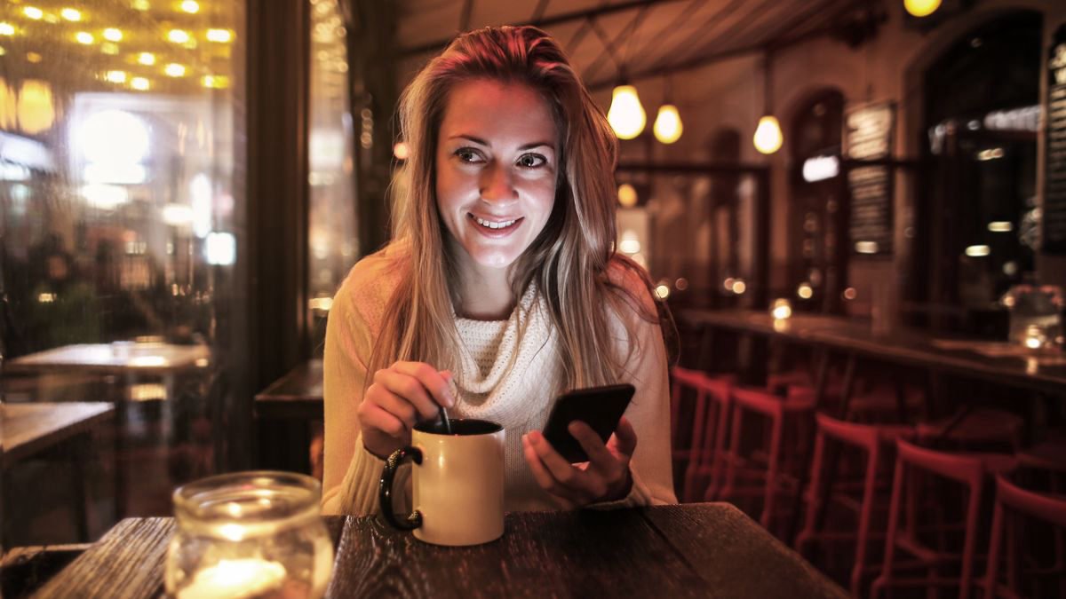 Smiling woman sitting at a cafe table in the evening