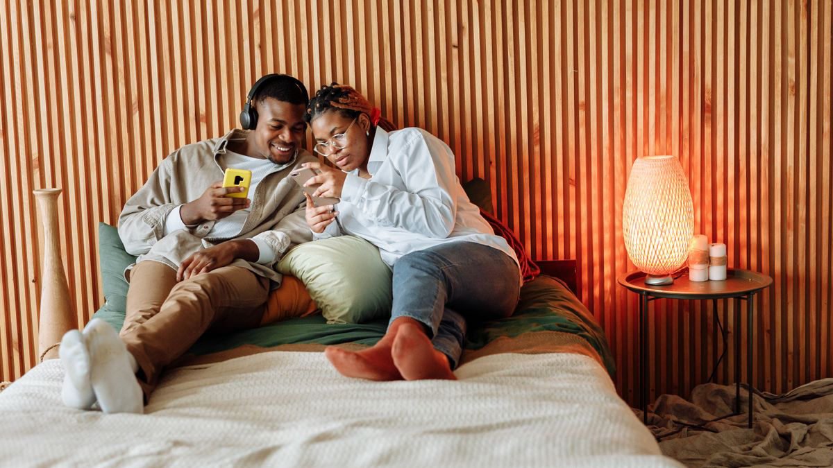 Couple relaxing in a bedroom while using their smartphones