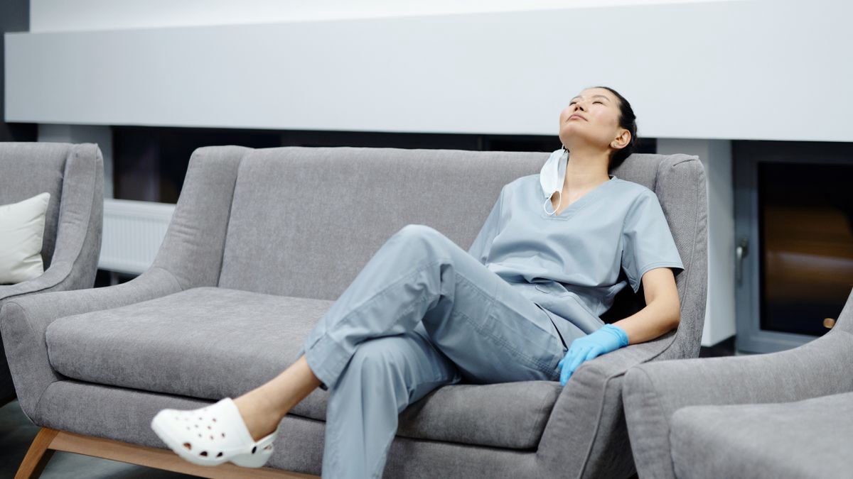 Nurse in scrubs resting on a couch during a break