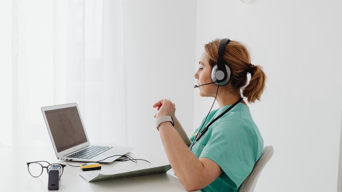 Healthcare worker wearing a headset during an online consultation on a laptop
