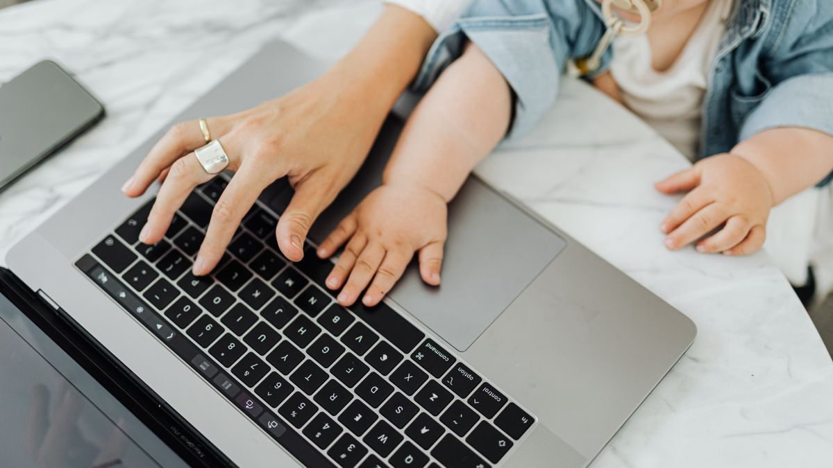 Mother and baby with their hands on a laptop keyboard