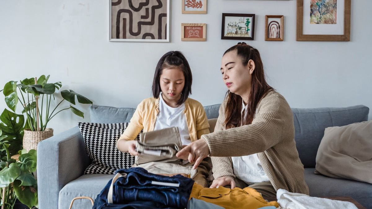 Mother and daughter folding laundry together on a sofa